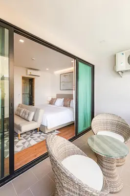 a bedroom with a bed and two chairs at The Proud Rawai Resort in Rawai Beach