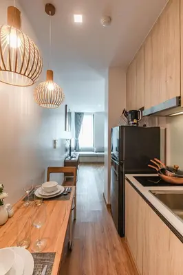 a kitchen with a table and a black refrigerator at The Proud Rawai Resort in Rawai Beach