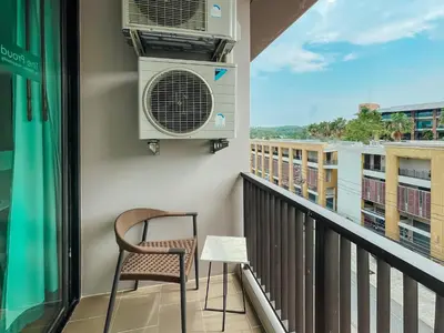 a balcony with a chair and a air conditioner at The Proud Rawai Resort in Rawai Beach