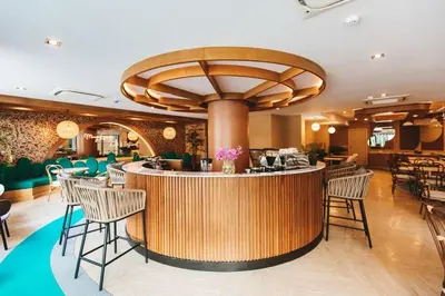 a restaurant with a bar with chairs and tables at The Proud Rawai Resort in Rawai Beach