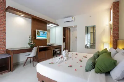 a bedroom with a bed and a desk in a room at Tuana Hotels Brook Pool Access in Chalong