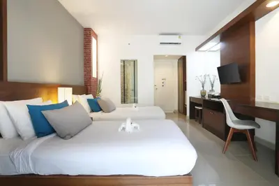 a bedroom with two beds and a desk with a computer at Tuana Hotels Brook Pool Access in Chalong