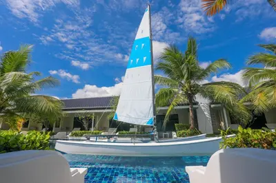 a sail boat in front of a house with a swimming pool at Tuana Hotels Brook Pool Access in Chalong