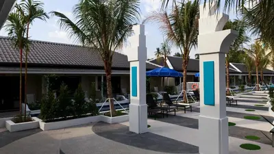a courtyard with palm trees and a building at Tuana Hotels Brook Pool Access in Chalong