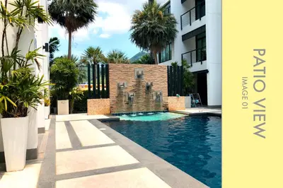 a swimming pool in the middle of a building with palm trees at Pool Access 2 BDR Stylish Condo in Kamala Beach