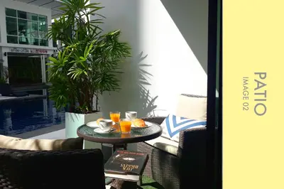 a table with two glasses of orange juice on a patio at Pool Access 2 BDR Stylish Condo in Kamala Beach