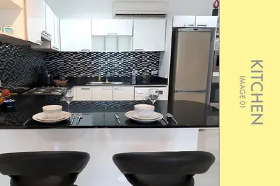 a kitchen with black and white cabinets and two stools at Pool Access 2 BDR Stylish Condo in Kamala Beach