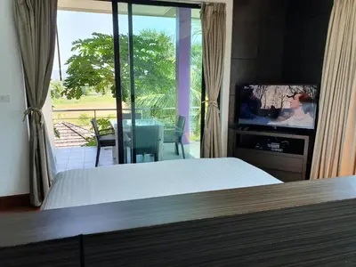 a bedroom with a bed and a tv and a balcony at Eden Villa Phuket in Bang Tao Beach