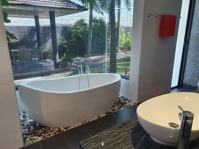a bath tub sitting next to a window in a bathroom at Eden Villa Phuket in Bang Tao Beach