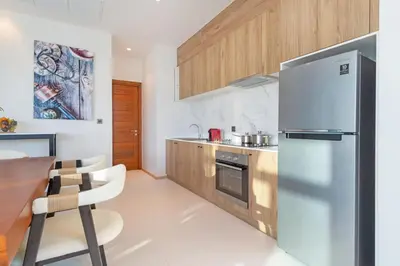 a kitchen with a stainless steel refrigerator and wooden cabinets at Shambhala Grand Villa - Private Pool Villas by Escape Villas - Top Choice - Guest Favorite - Best Location in Bang Tao Beach