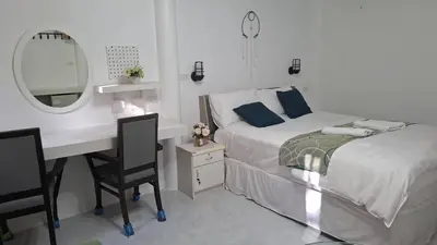 a bedroom with a bed and a desk and a mirror at Suwita House in Nai Yang Beach