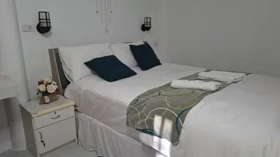 a white bed with blue pillows and a night stand at Suwita House in Nai Yang Beach