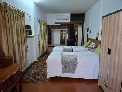 a bedroom with two beds and a dresser in it at Suwita House in Nai Yang Beach