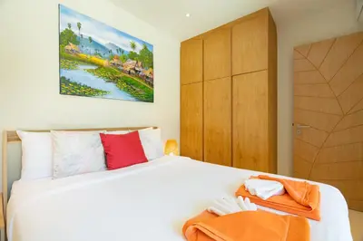 a bedroom with a white bed and a wooden cabinet at 3BR Villa with Private Pool in Trichada Sky at Bangtao Beach in Bang Tao Beach