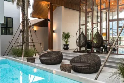 a swimming pool with wicker chairs next to a swimming pool at Apartment at Palmyrah Surin by Lofty in Surin Beach