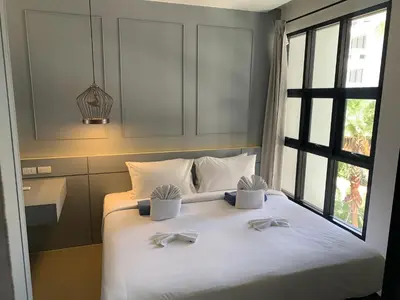a bedroom with a large white bed with a window at Apartment at Palmyrah Surin by Lofty in Surin Beach