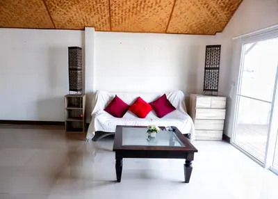 a living room with a white couch with red pillows at Kingsacre in Nai Yang Beach