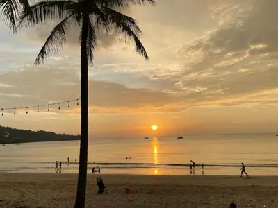 a group of people on the beach at sunset at Villa Luxe AP06 in Kamala Beach