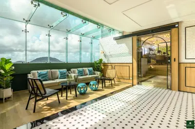 a balcony with a couch and a table and chairs at Hilltop Wellness Resort Phuket in Phuket Town