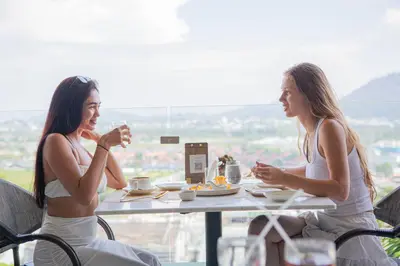 two women sitting at a table eating food at Hilltop Wellness Resort Phuket in Phuket Town