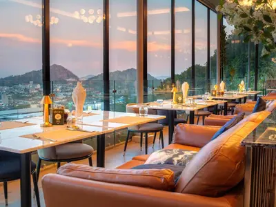 a restaurant with tables and chairs and large windows at Hilltop Wellness Resort Phuket in Phuket Town