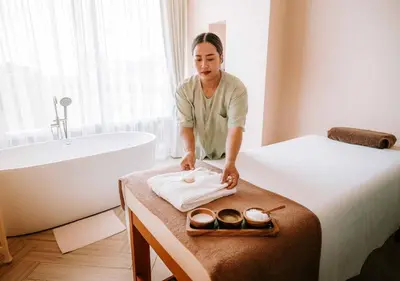a woman standing next to a bed in a bathroom at Hilltop Wellness Resort Phuket in Phuket Town