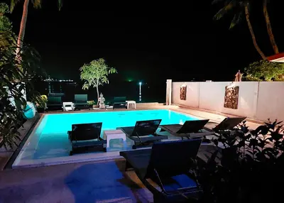 a swimming pool at night with chairs and tables at Mango Tree Villa in Panwa Beach