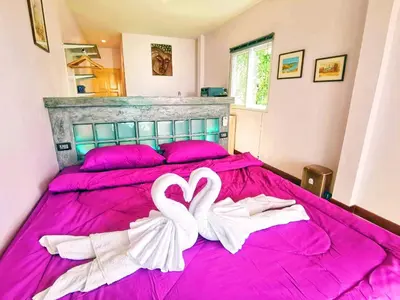 two white swans are sitting on a pink bed at Mango Tree Villa in Panwa Beach