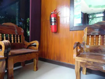 a fire extinguisher hanging on a wall next to two wooden chairs at Tubkaek mansion in Tab Kaek Beach