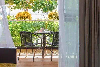 a table with two chairs and a cup of coffee on a balcony at Davina Beach Homes in Panwa Beach
