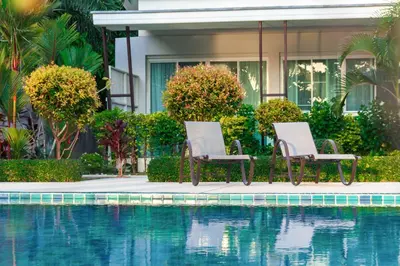 two chairs sitting next to a swimming pool at Davina Beach Homes in Panwa Beach