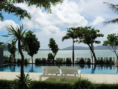 two white chairs sitting next to a swimming pool at Davina Beach Homes in Panwa Beach