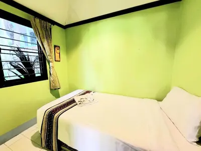 a green room with a bed with a window at Kata Garden Resort SHA Extra Plus in Kata Beach