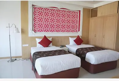 two beds in a room with a red picture on the wall at Lucky Sun Patong in Patong Beach