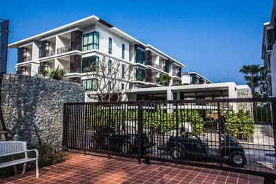 a building with cars parked in front of it at The Title Beach Front in Rawai Beach