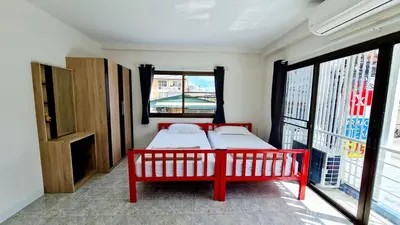 a bedroom with a red bed and a large window at TP House@Naka in Phuket Town