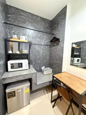 a kitchen with a table and a microwave on a wall at Ideo Phuket Hotel - Naiyang Beach in Nai Yang Beach