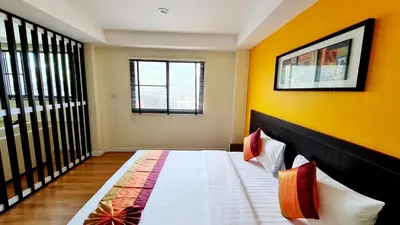 a bedroom with a bed with a yellow wall at TP House at town in Phuket Town