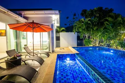 a swimming pool with chairs and an orange umbrella at 3 Bedroom Exclusive Private Pool Villa Smooth as Silk in Ao Nang Beach
