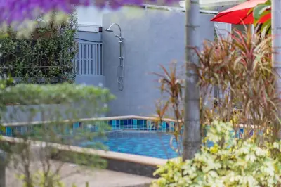 a swimming pool with a red umbrella in a garden at Honeybee Pool Villa Smooth as Silk in Ao Nang Beach