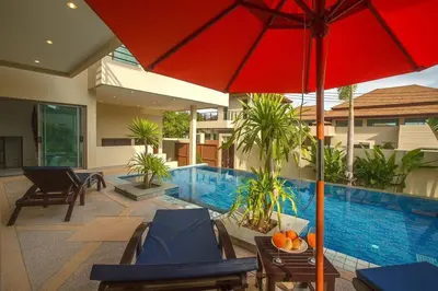 a house with a swimming pool with a red umbrella at Shanti Villas x MonthStayZ Thailand in Rawai Beach