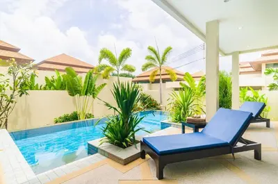a patio with a blue chair and a swimming pool at Shanti Villas x MonthStayZ Thailand in Rawai Beach