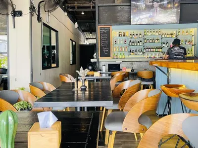 a restaurant with tables and chairs and a bar at Breakers Hotel Rawai in Rawai Beach