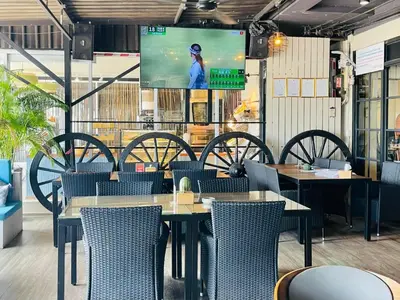 a restaurant with tables and chairs and a screen at Breakers Hotel Rawai in Rawai Beach
