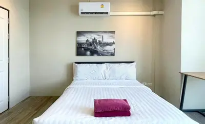 a bedroom with a white bed with a red pillow on it at Breakers Hotel Rawai in Rawai Beach