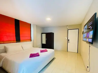 a bedroom with a white bed and a tv at Breakers Hotel Rawai in Rawai Beach