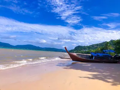 a boat sitting on the shore of a beach at Sea Dreamer Beachfront Apartments in Phuket Town