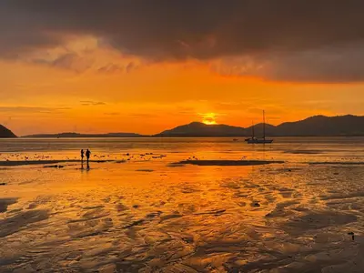 two people standing on the beach at sunset at Sea Dreamer Beachfront Apartments in Phuket Town