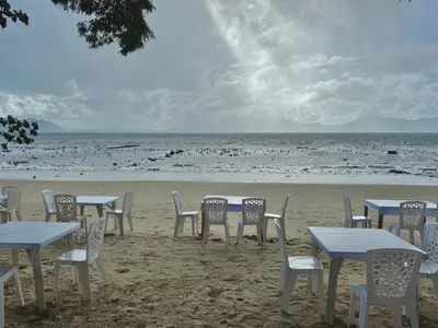 a group of tables and chairs on the beach at Sea Dreamer Beachfront Apartments in Phuket Town