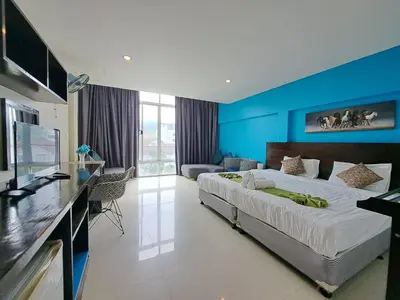 a bedroom with a large bed and a blue wall at Baan Oui guest house - Nai Harn in Phuket Town